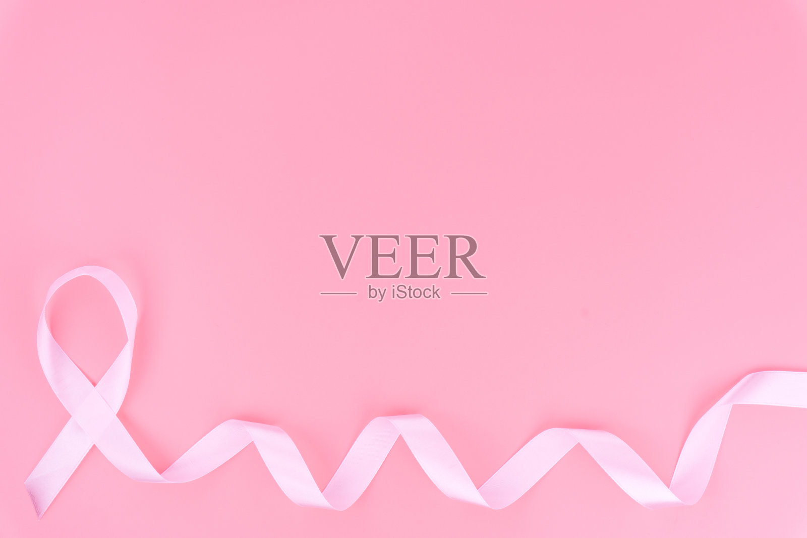 粉色丝带乳腺癌在粉红色背景与复制空间的文本。平躺，俯视图。照片摄影图片