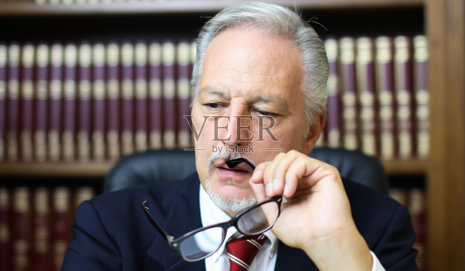 一个深思熟虑的经理在他的办公室里拿着眼镜的肖像照片摄影图片