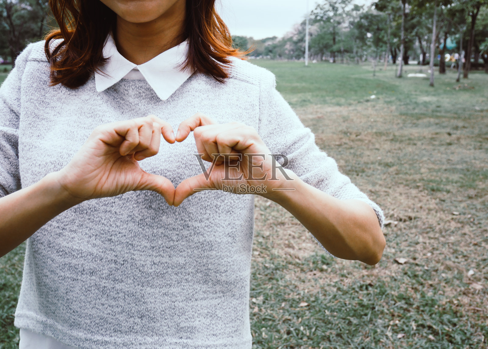 美丽的亚洲女人微笑肖像和手显示心脏标志。照片摄影图片