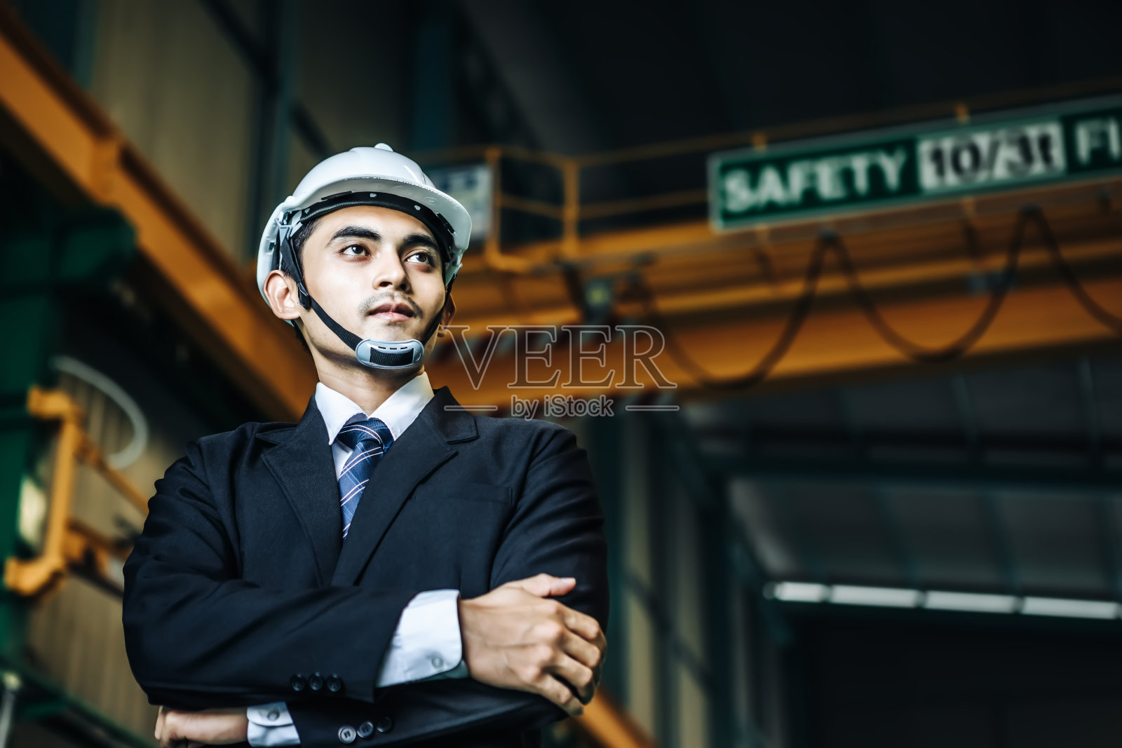 工程师或商人戴着头盔站在重型工厂前。照片摄影图片