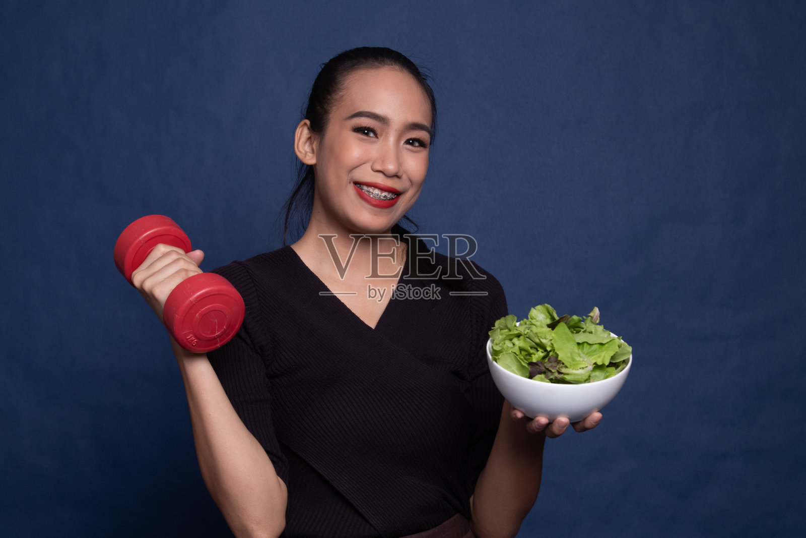 健康的亚洲女人，拿着哑铃和沙拉。照片摄影图片