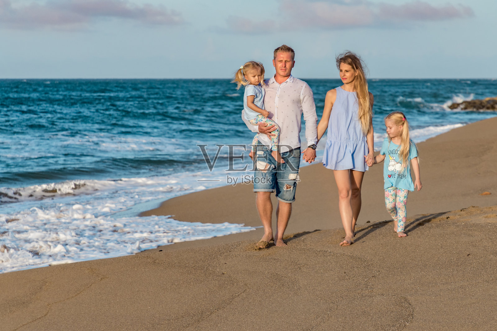 快乐的四口之家:妈妈，爸爸和两个女儿在海滩上散步照片摄影图片