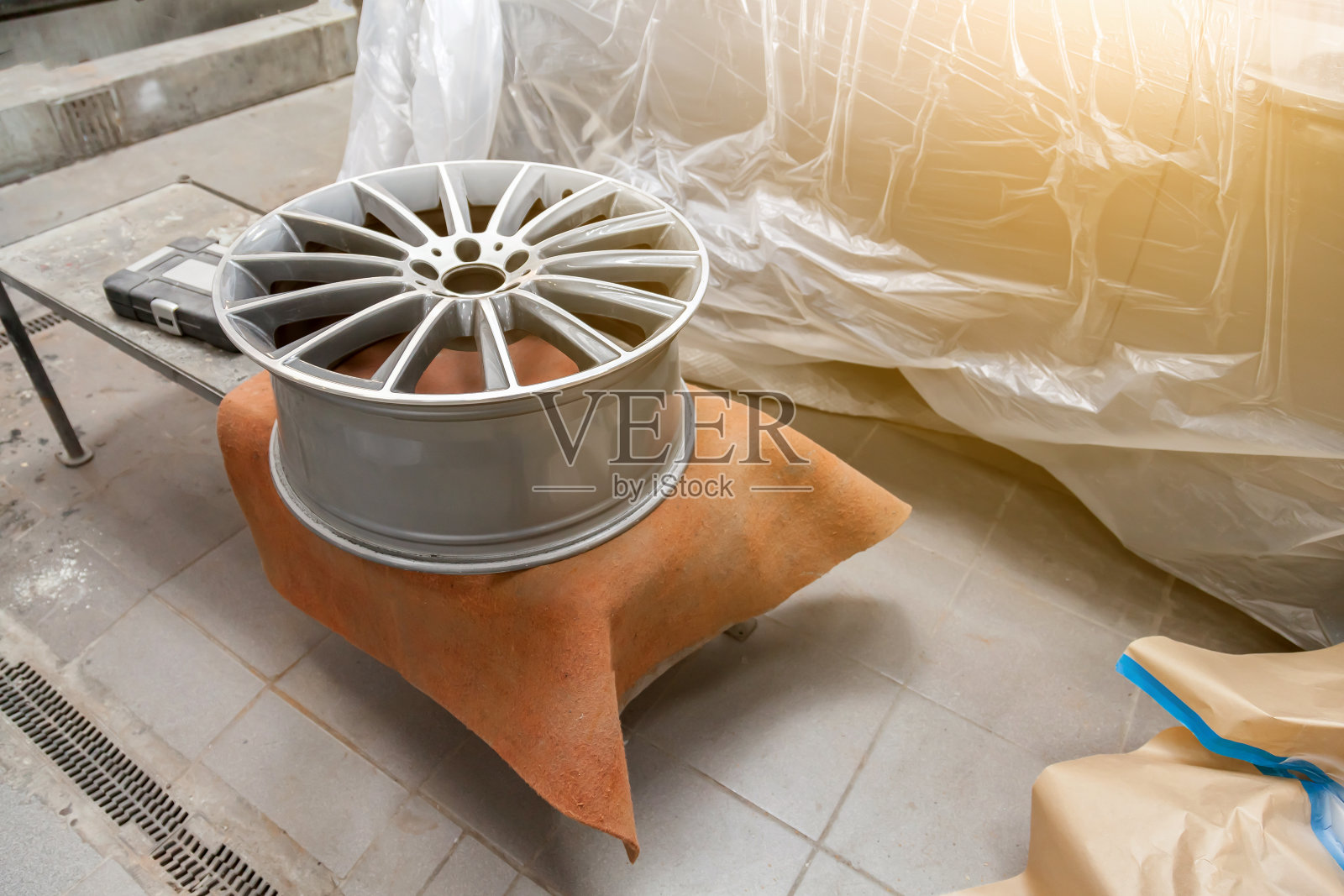 在车间对汽车铝盘表面进行后续喷漆准备，利用研磨材料对车轮进行清理平整。汽车服务行业。照片摄影图片