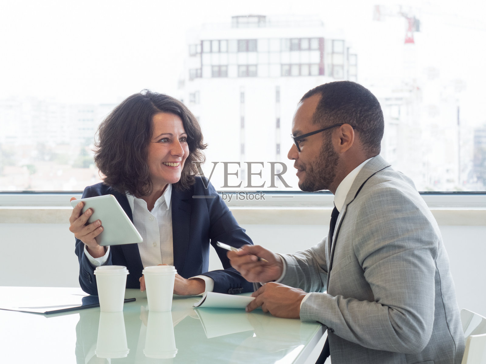 微笑的同事用平板电脑工作照片摄影图片