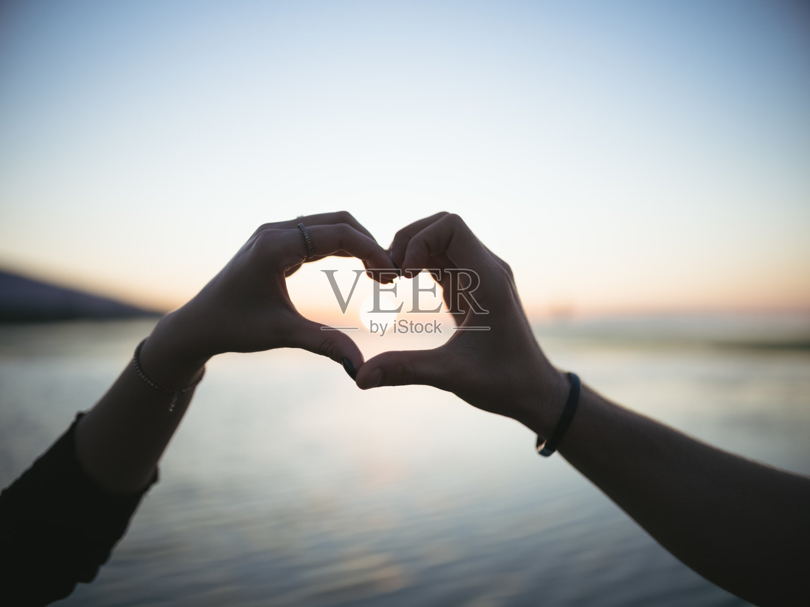 情侣在黄昏时做心形象征照片摄影图片