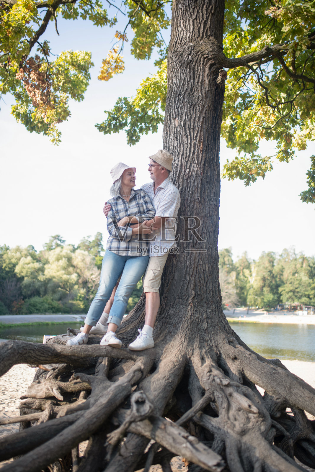 一对成年夫妇站在一棵大树的根部照片摄影图片