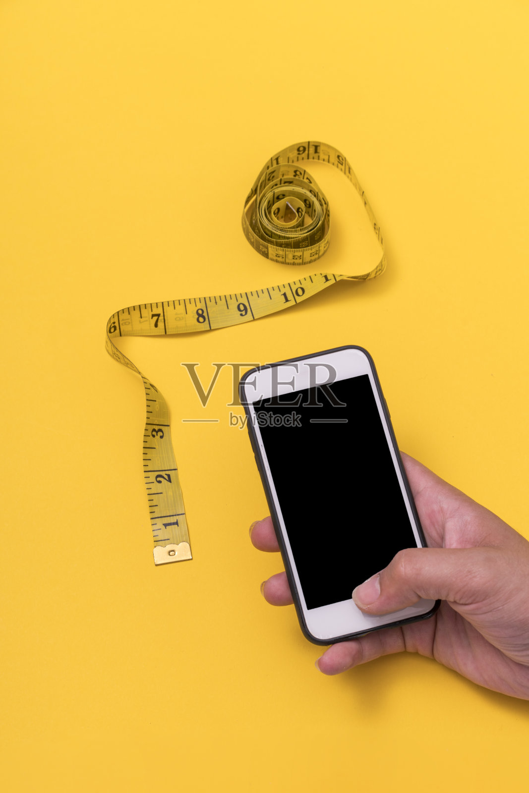 黄色背景的卷尺和手机照片摄影图片