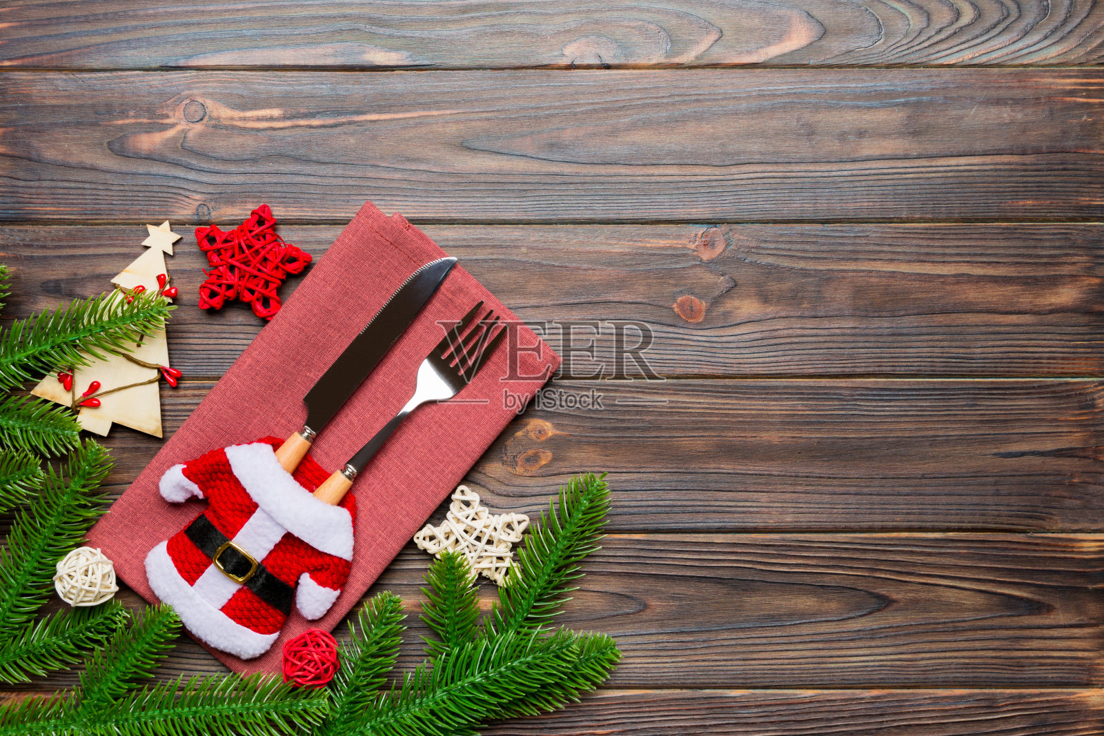 俯视图的叉和刀放在圣诞衣服餐巾上圣诞装饰和新年树在木制的背景。假日和节日的概念与复制空间照片摄影图片