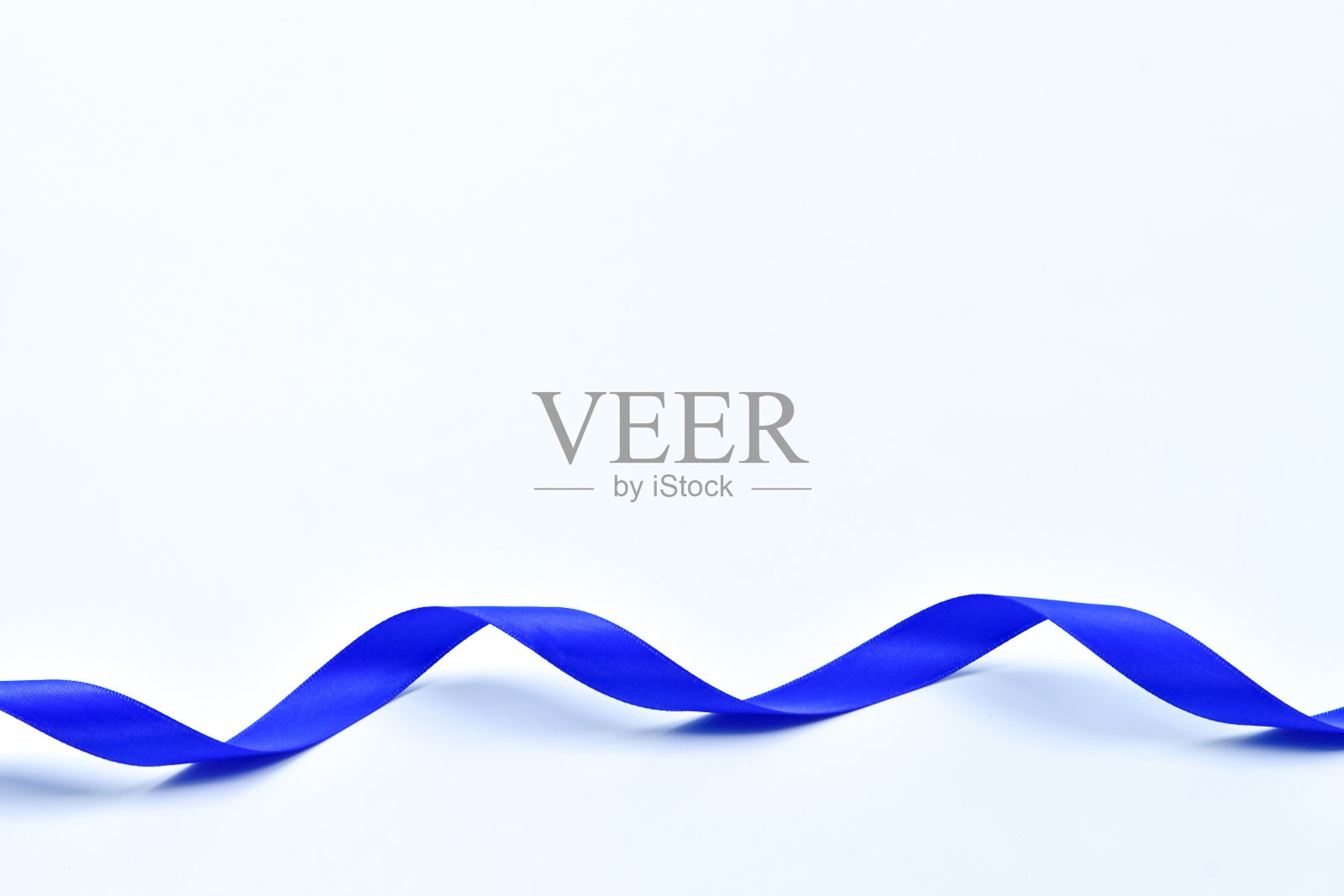 白色背景上的蓝色卷曲缎带，装饰元素照片摄影图片