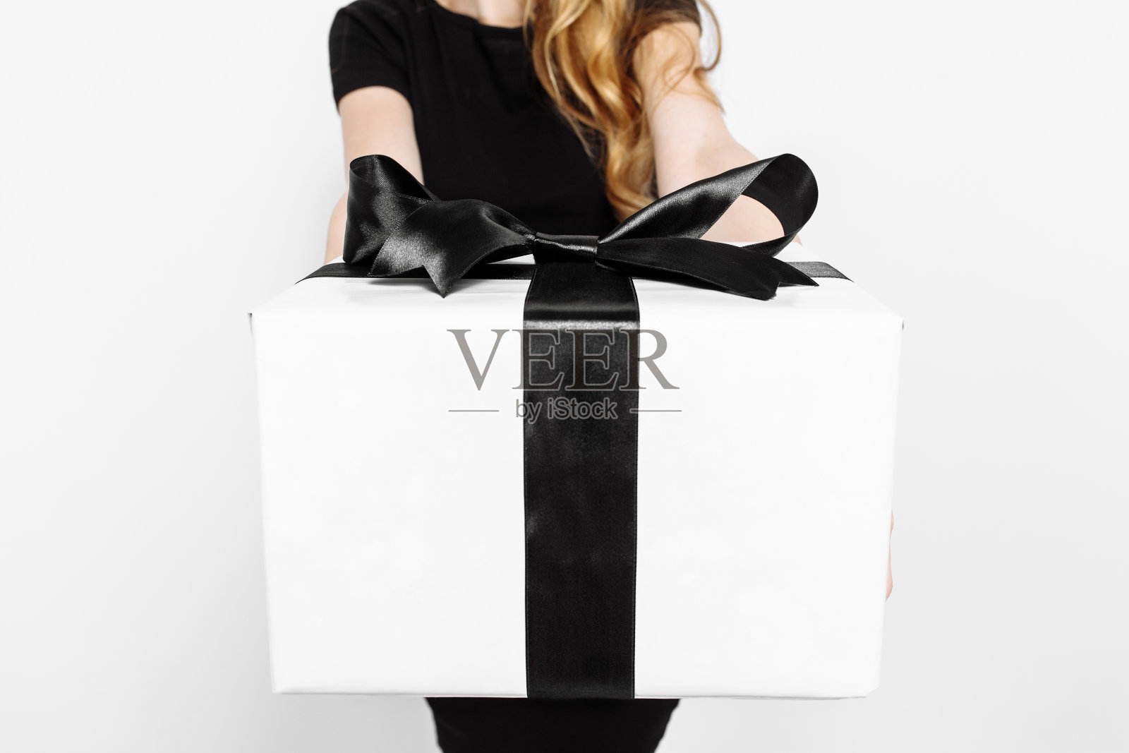 一个女孩拿着一个礼物盒黑色黑色的星期五蝴蝶结，在一个白色的背景。照片摄影图片