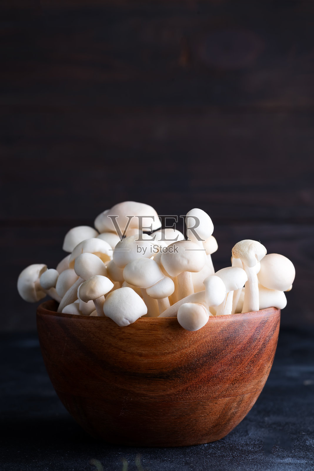 白色的布纳-shimeji在木制的乡村碗在石头的黑色背景照片摄影图片