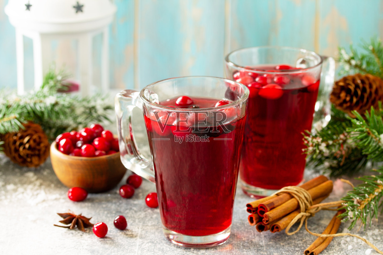 圣诞节的饮料。热的冬季饮料，蔓越莓和肉桂放在一个轻石桌上。为你的文本留出空间。照片摄影图片