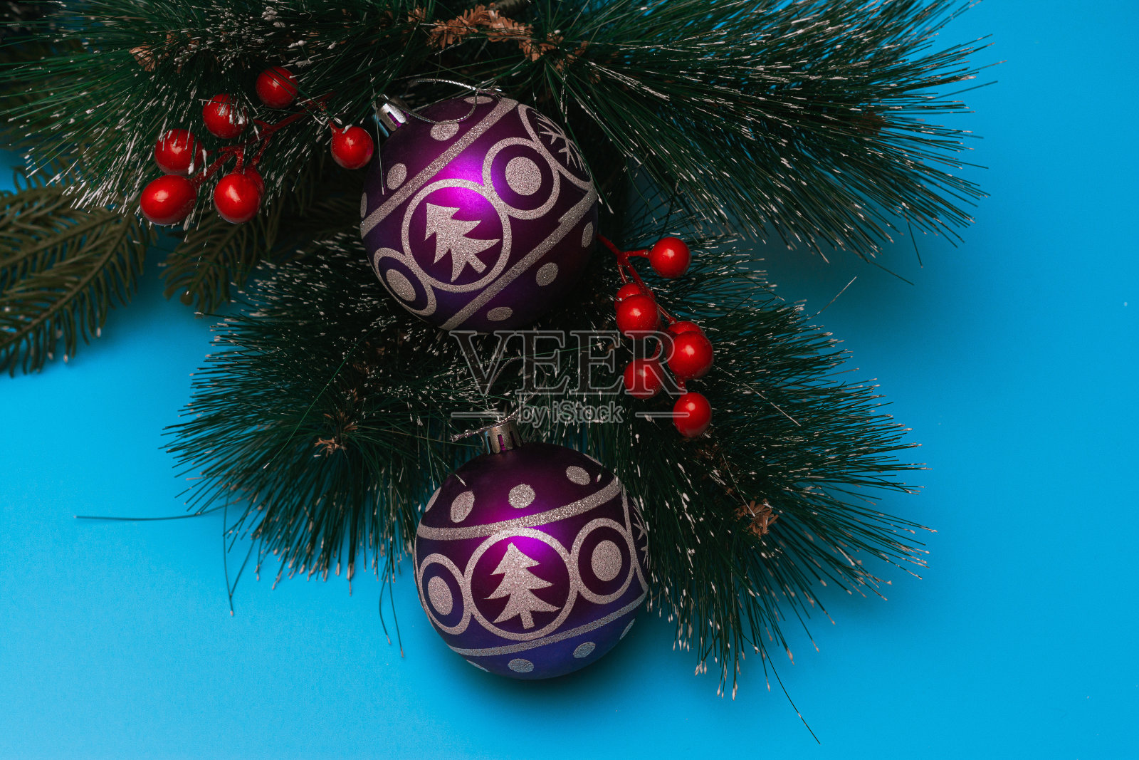 两个紫色的气球和圣诞树和雪花的形象躺在云杉的人造树枝上，蓝色的背景，平躺照片摄影图片