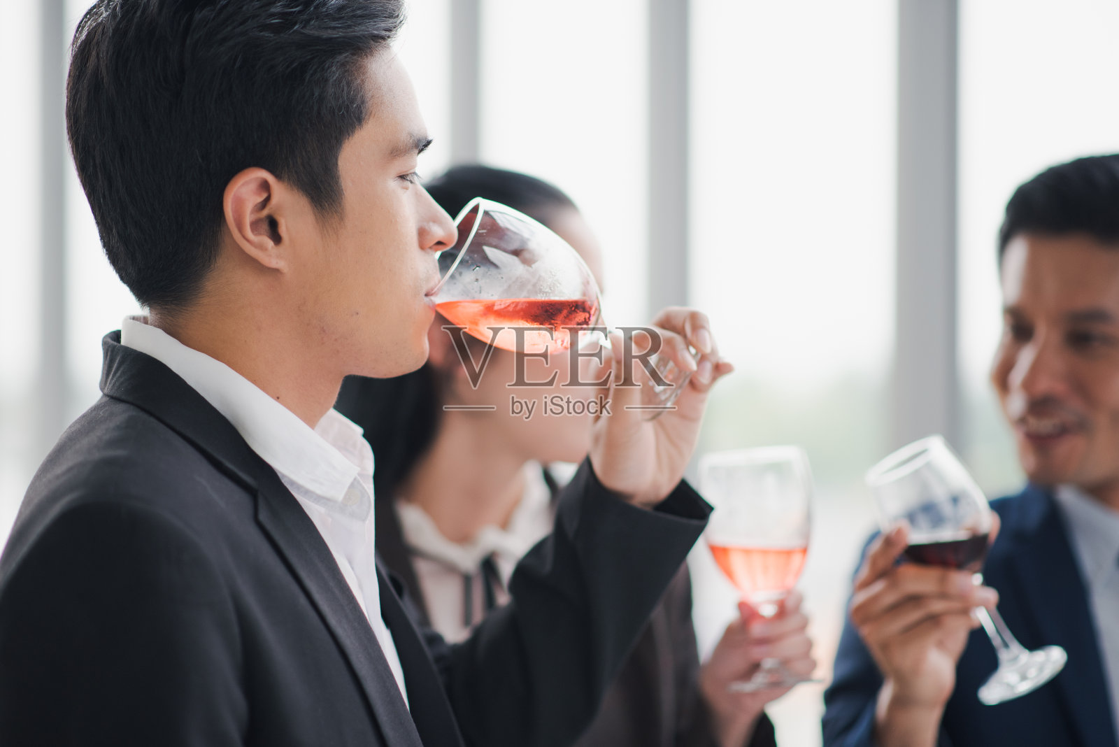 年轻的亚洲同事朋友一起在办公室喝鸡尾酒。在公司办公室举行的新年聚会上，一群商务人士微笑着，心情愉快照片摄影图片