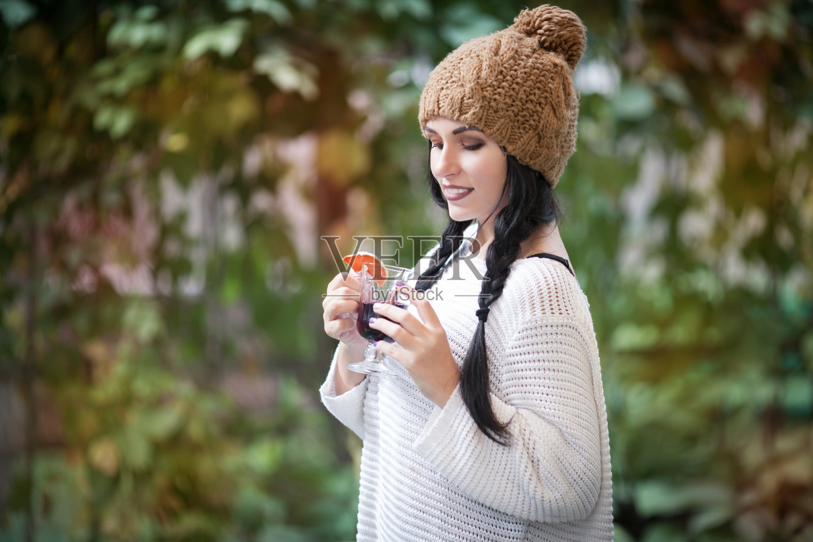 年轻美丽的女子在秋天的户外喝热饮。照片摄影图片
