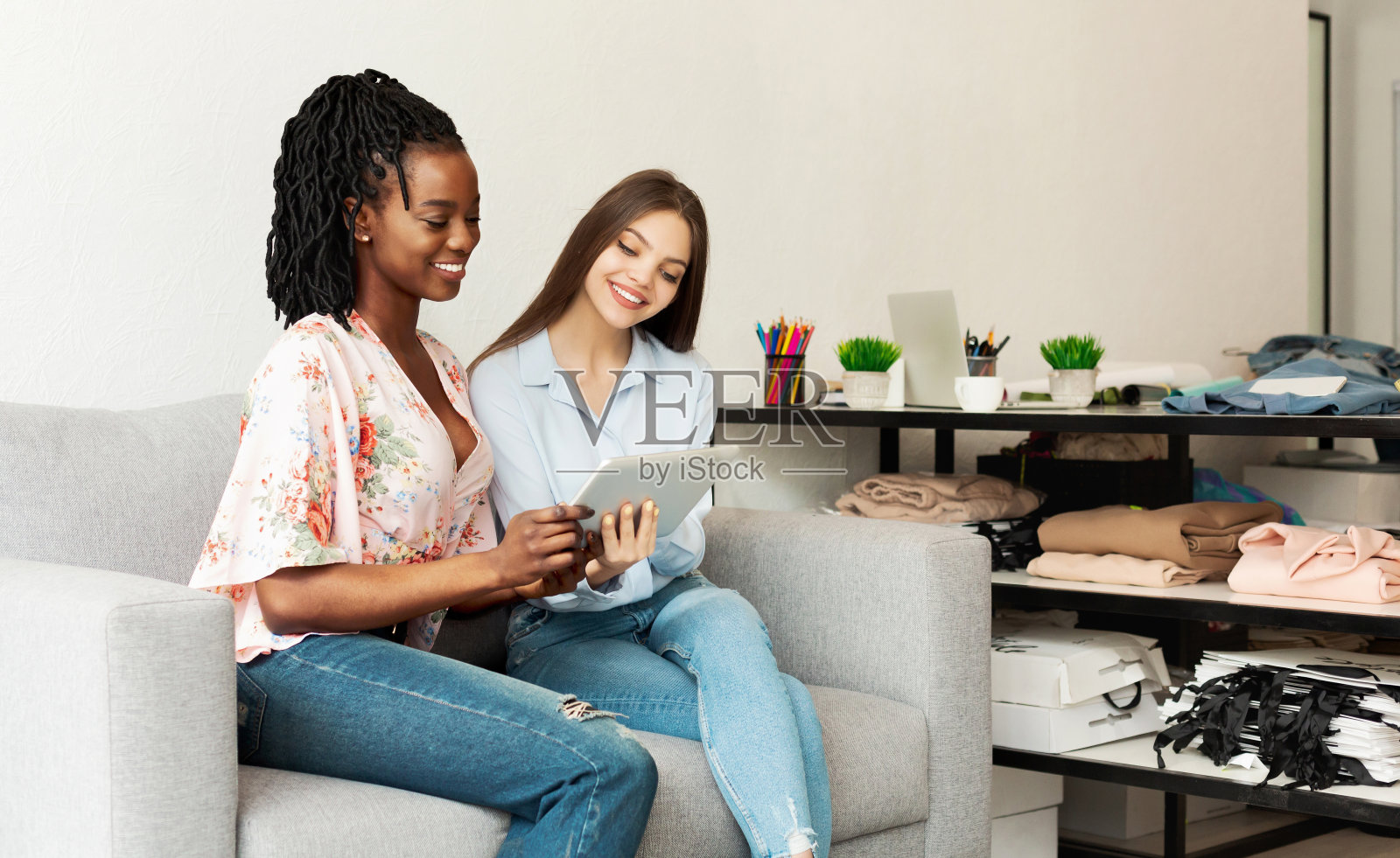 时尚设计师和客户在室内沙发上使用平板电脑照片摄影图片