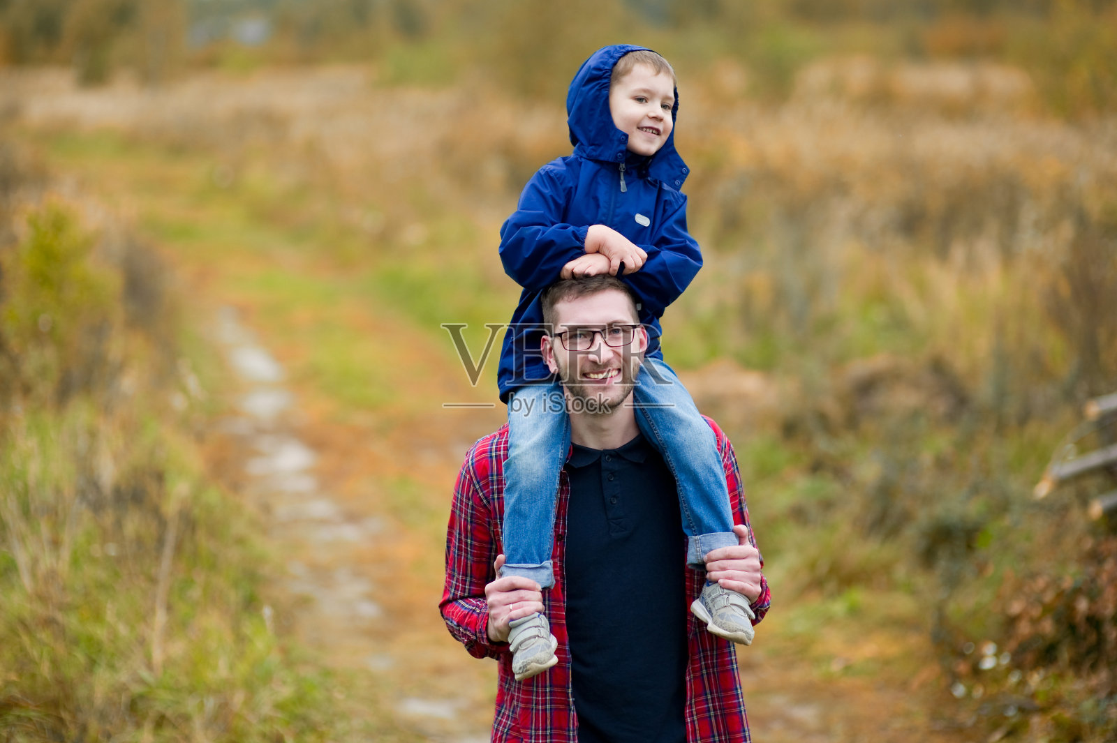 儿子坐在父亲的肩膀上。在乡间散步照片摄影图片