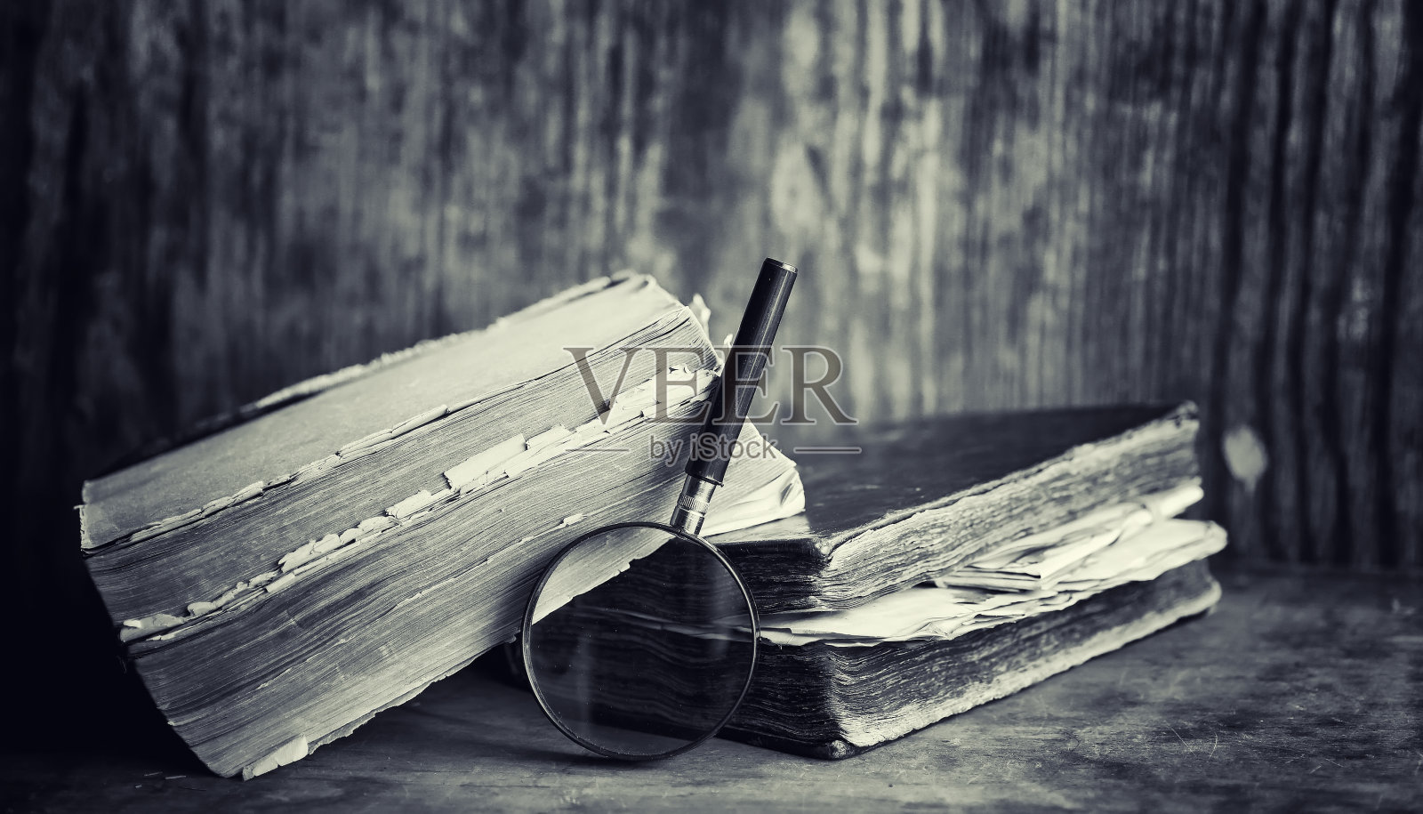 桌上放着一本旧书。一本历史百科全书放在一个旧的木制工作台上。一本生物学的旧书，一本对开本，一本宪法，一本圣经。照片摄影图片