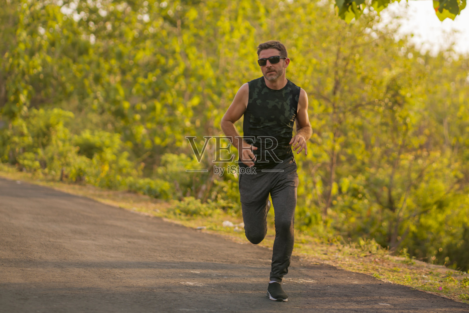 年轻有吸引力和健康的男人的生活方式肖像在他的30或40多岁在乡村公路上跑步做慢跑锻炼训练快乐在美丽的自然背景下健身和运动的概念照片摄影图片