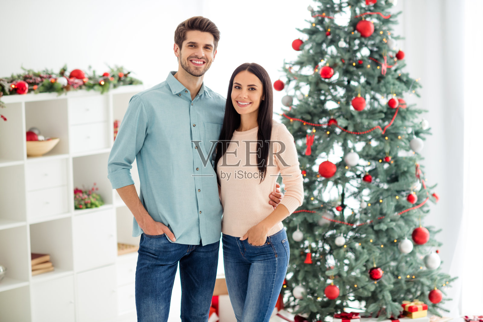 两个迷人的浪漫的人拥抱享受圣诞节时间圣诞节假期穿着粉红色的套头牛仔牛仔裤在房子里与noel室内装饰照片摄影图片