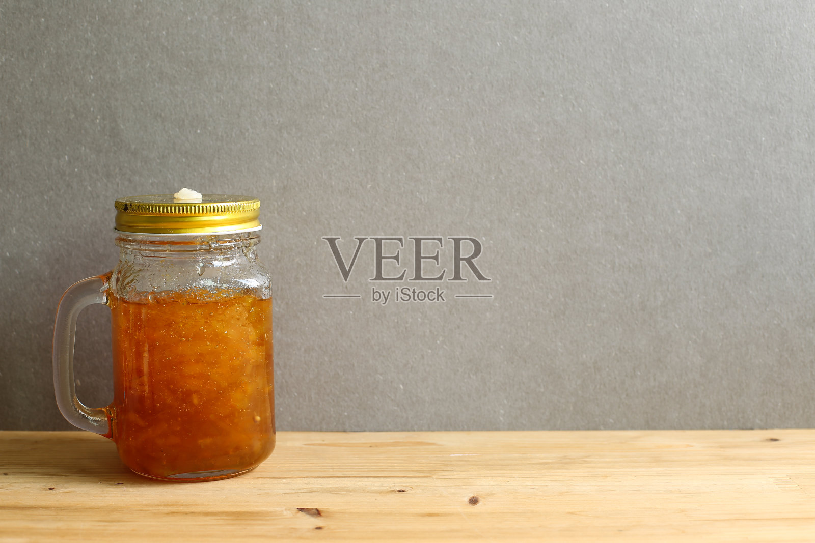 灰色背景的木桌上放着一只玻璃瓶里的香橼茶照片摄影图片