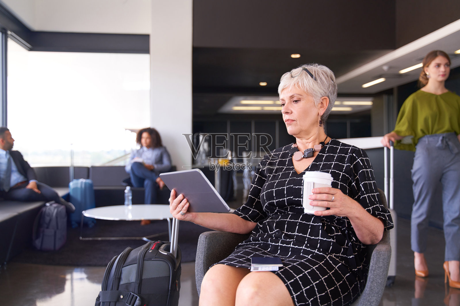 职业女性坐在机场穿着时髦的服装认真工作在平板喝咖啡照片摄影图片