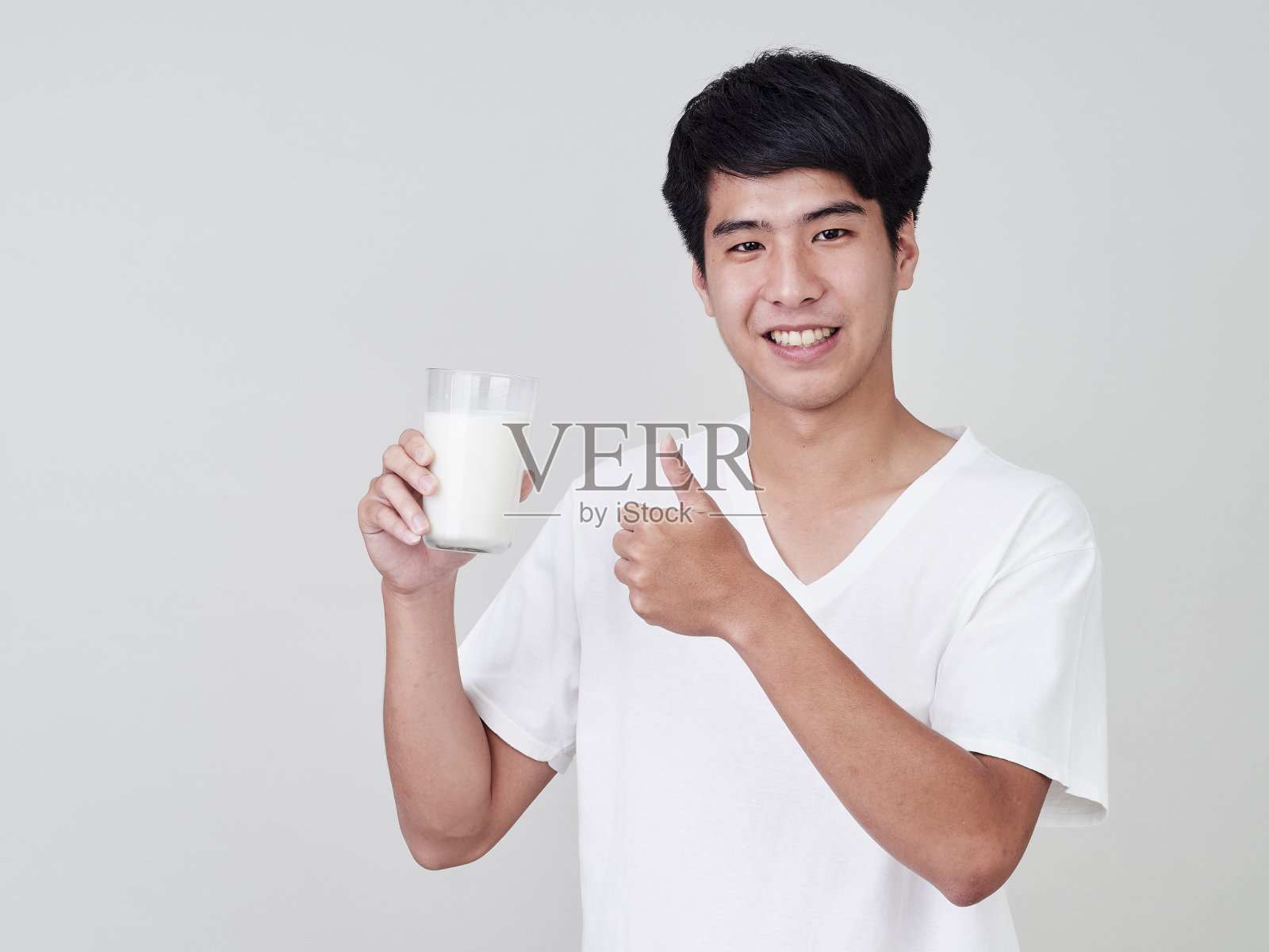 一个年轻人在白色背景上拿着牛奶杯的工作室肖像照片摄影图片