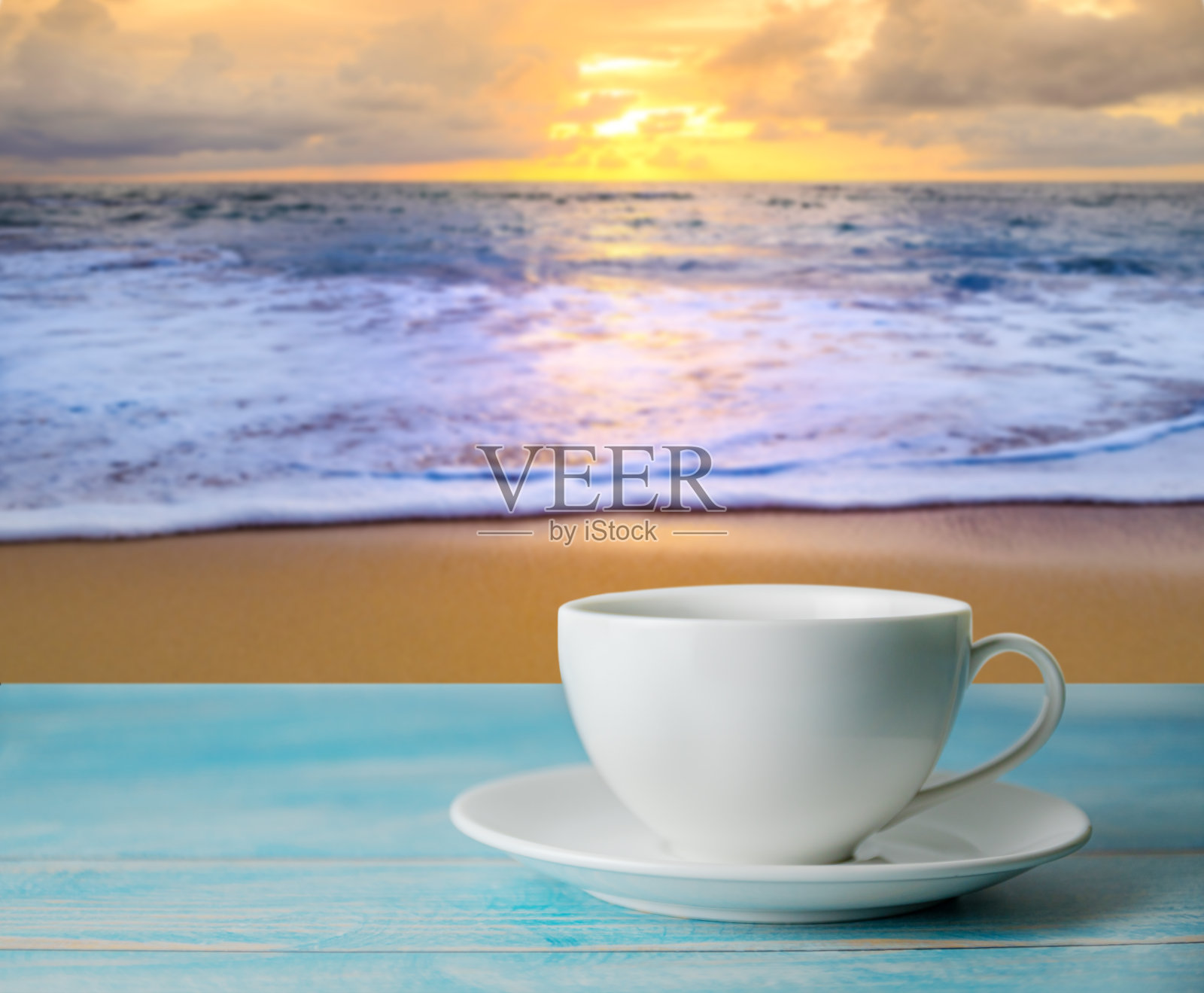 一杯咖啡与模糊的海滩日落或日出和色彩斑斓的云天空在黄昏照片摄影图片