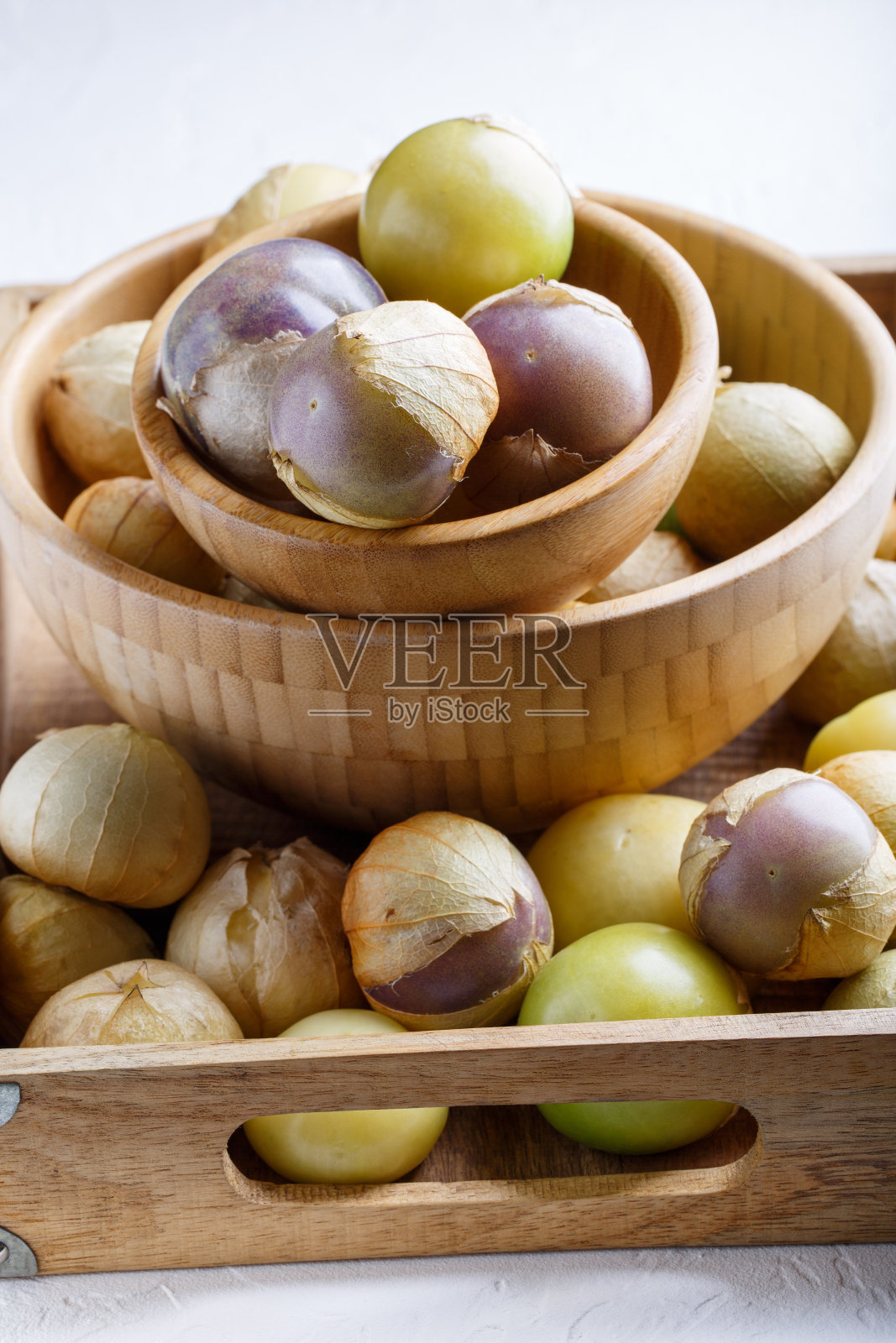 成熟的番茄(墨西哥去壳番茄，费城酸浆，蔬菜酸浆)放在木制托盘里，白色的桌子上。照片摄影图片