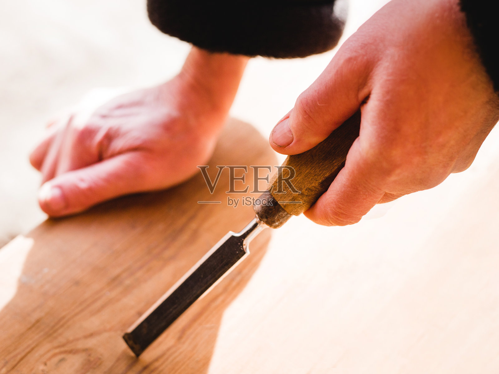 木工工作中，在工作台上手持凿子的木匠，将手持刀具工作的木匠的双手合在一起照片摄影图片