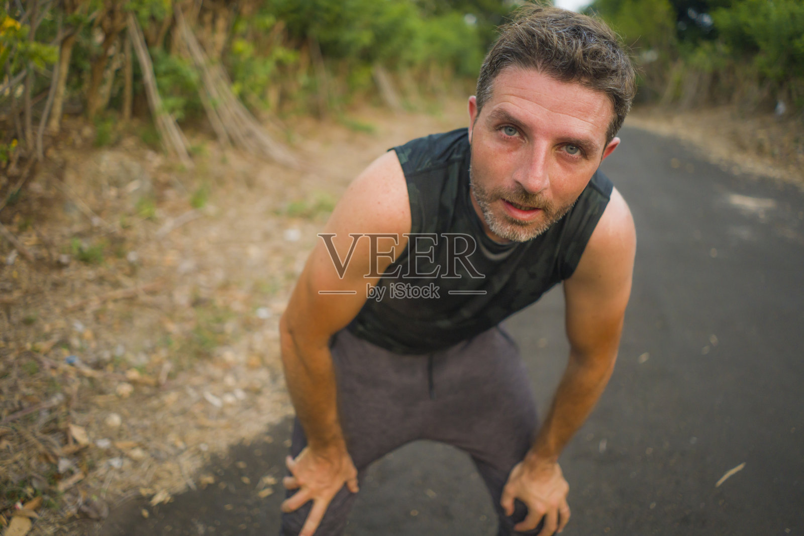 运动和健身的生活方式肖像，年轻有吸引力的出汗和疲倦的男人精疲力竭后，在美丽的乡村道路上跑步锻炼呼吸冷却后，努力训练照片摄影图片