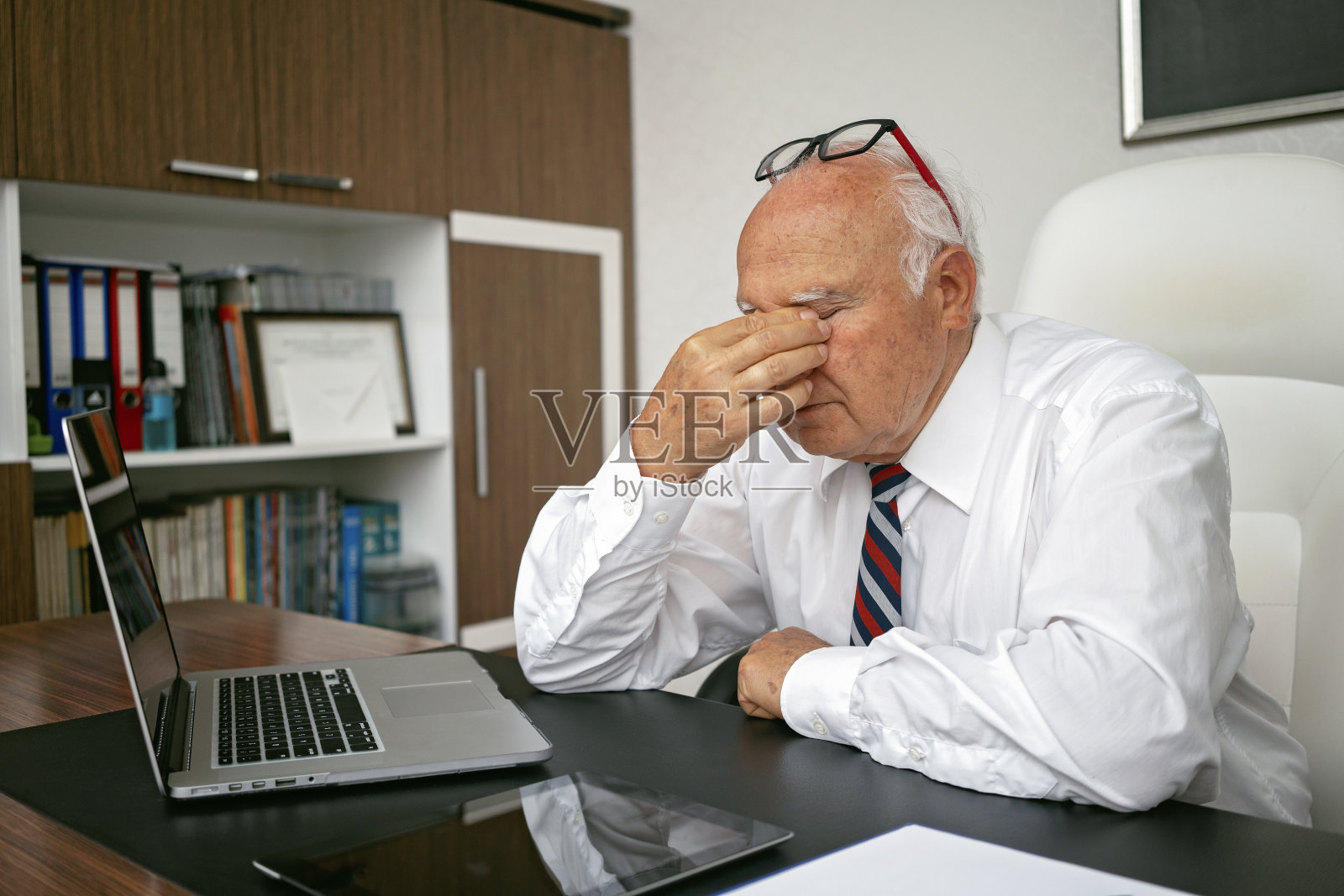 老男人累了，在笔记本电脑上工作。照片摄影图片