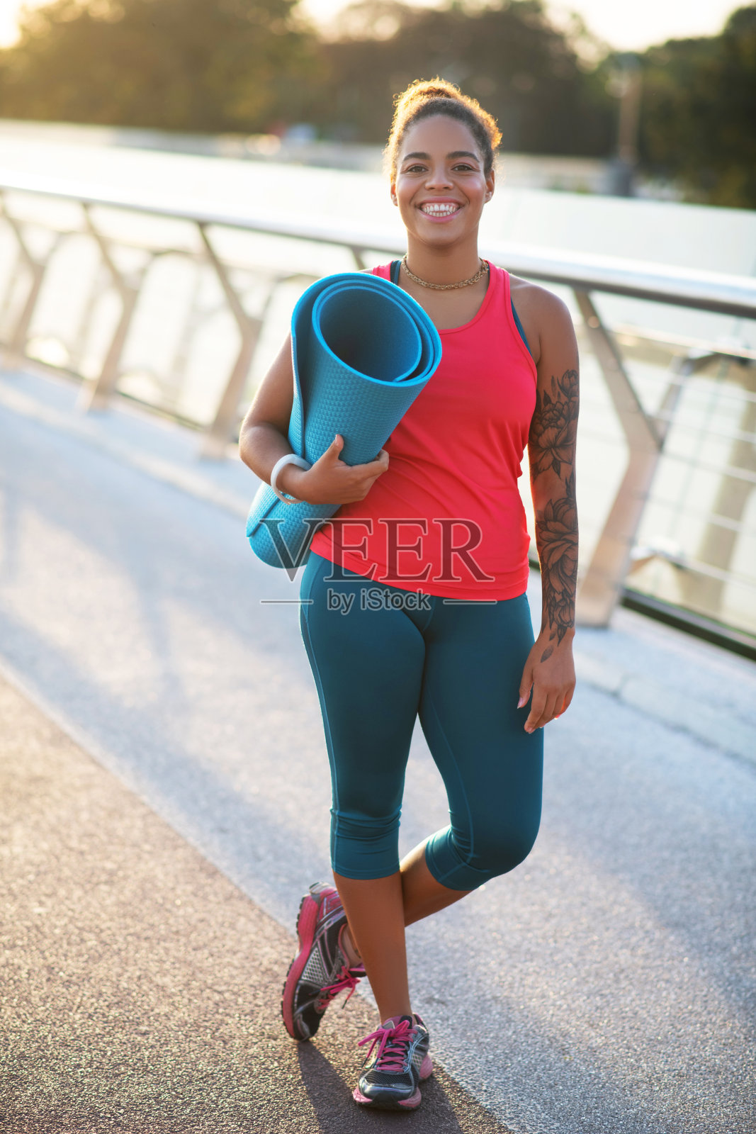 快乐的纹身女人穿着运动服拿着运动垫照片摄影图片