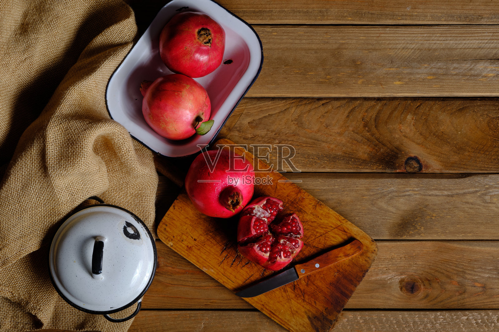 切菜板上的石榴水果的静物，剥落的沙发，旧的木制背景和瓷罐和托盘的装饰照片摄影图片
