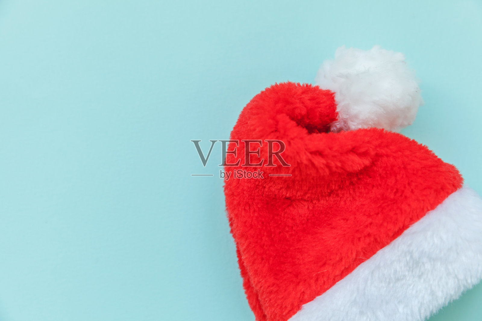 简单简约的圣诞老人帽设计孤立在蓝色柔和彩色时尚背景照片摄影图片