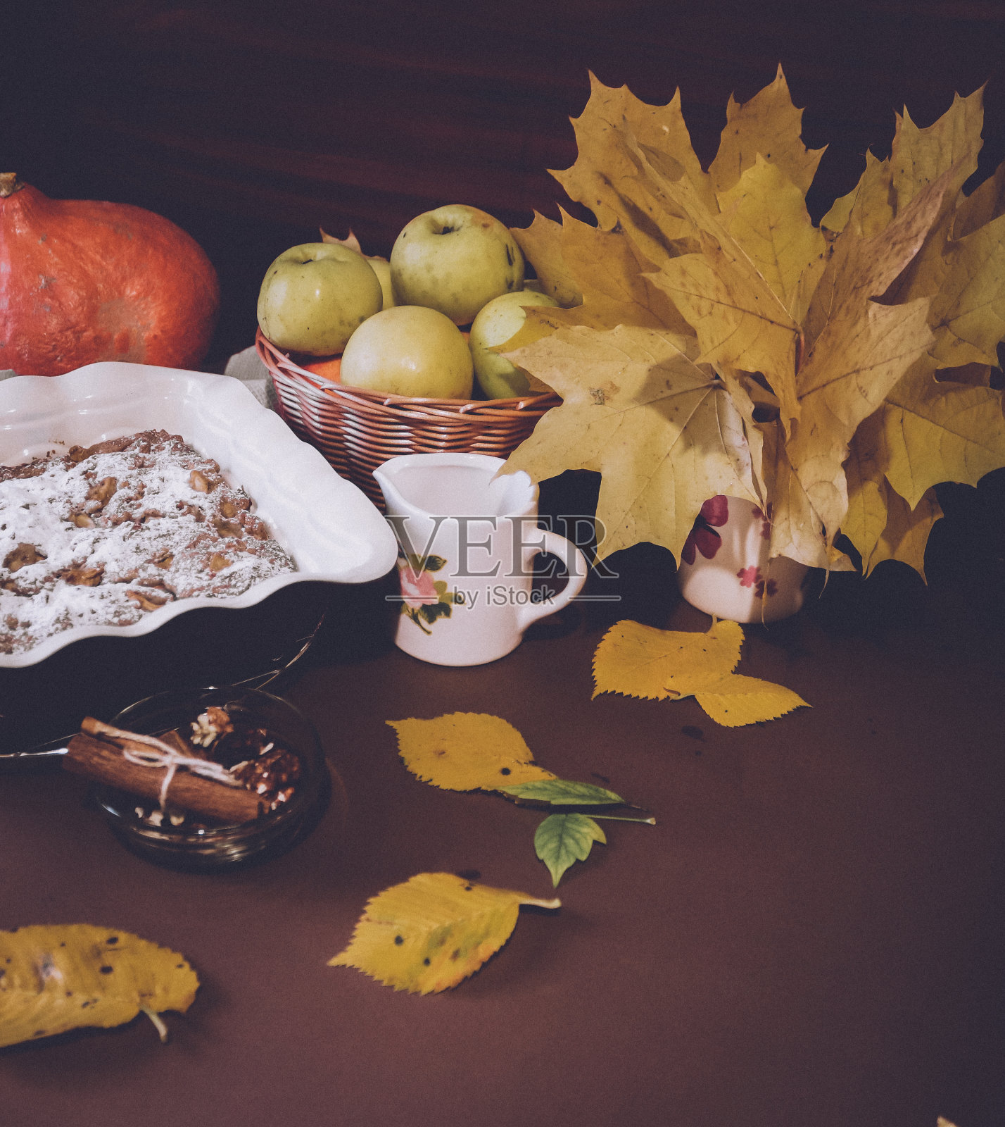 节日的苹果派与糖粉特写与秋天的叶子和南瓜在桌子上照片摄影图片