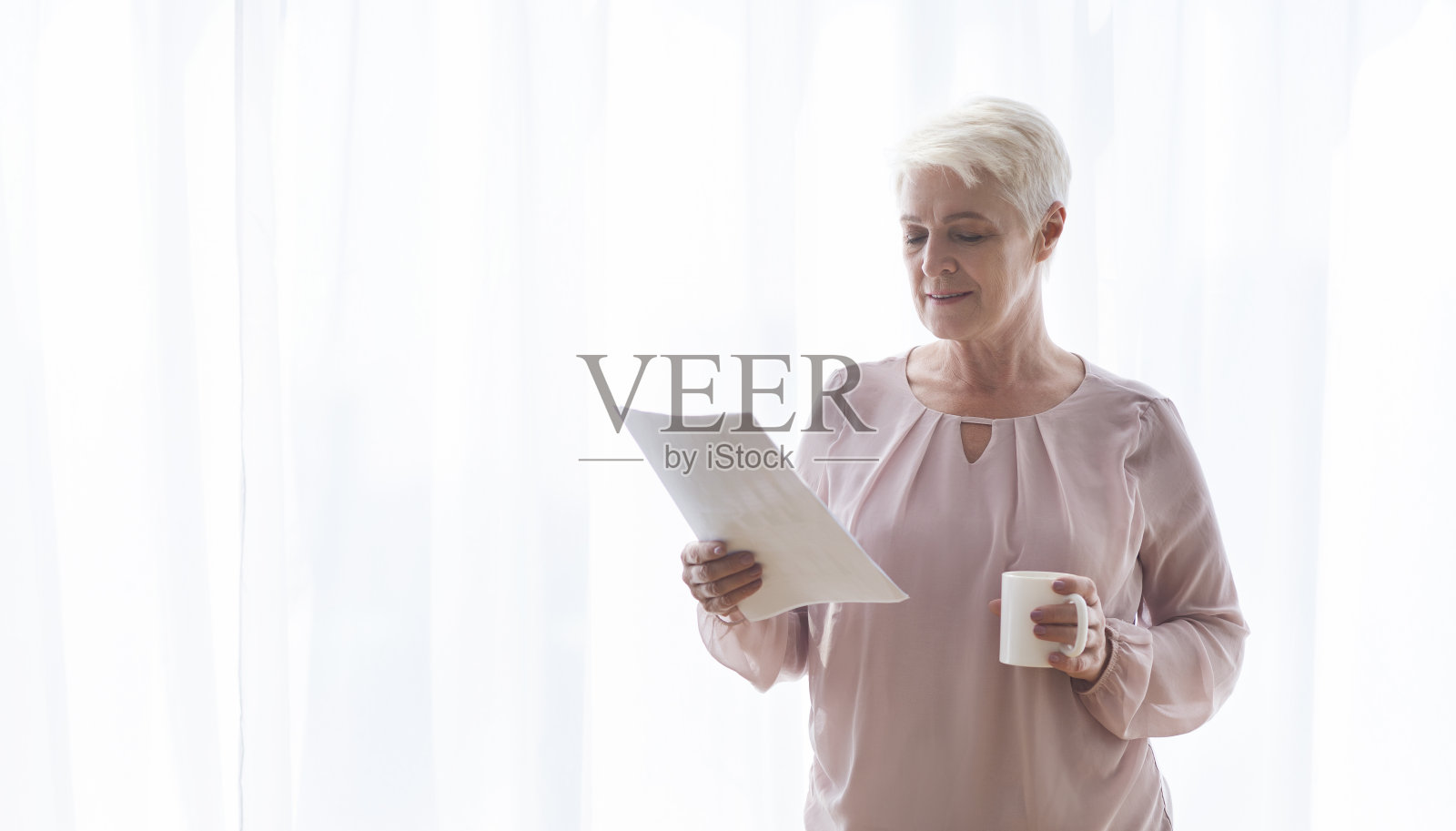 老女作家一边看手稿一边喝茶照片摄影图片