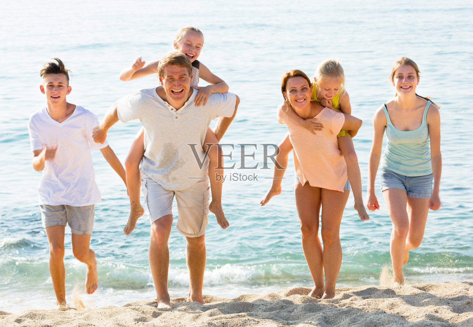 父母和孩子在沙滩上的肩膀上照片摄影图片