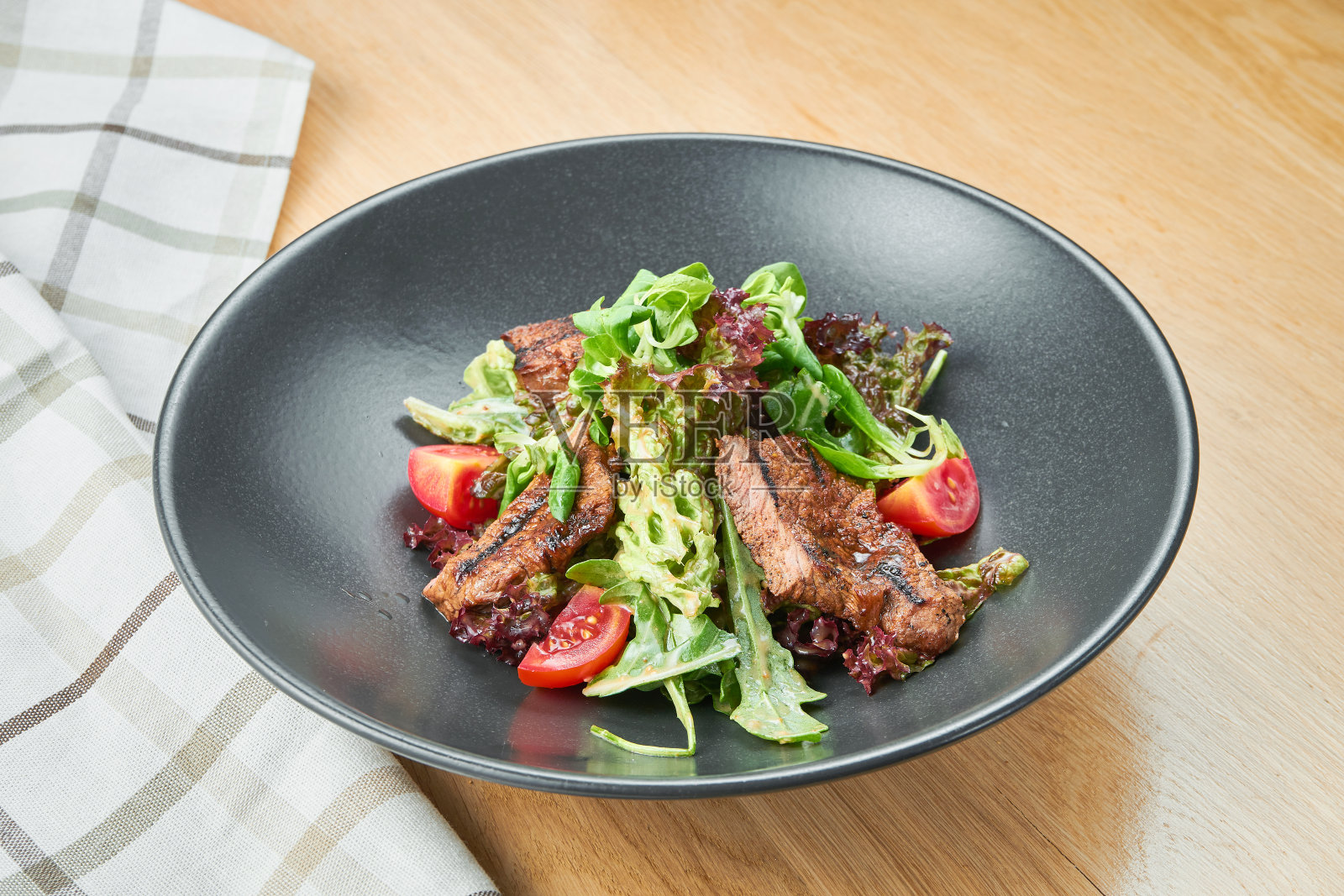烤小牛肉沙拉配生菜，樱桃番茄，或蓝奶酪在一个黑色的碗在木制的背景。选择性聚焦，c;向上照片摄影图片