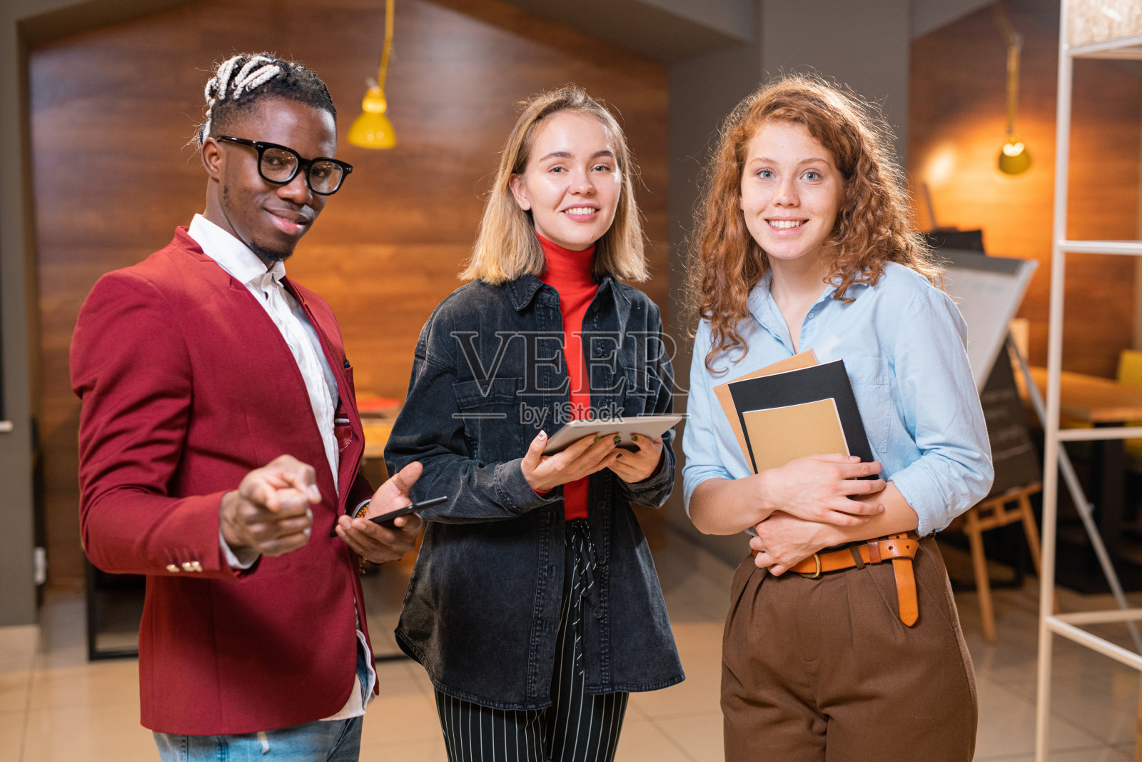 年轻优雅的非洲男人拿着智能手机和两个漂亮随意的女孩照片摄影图片
