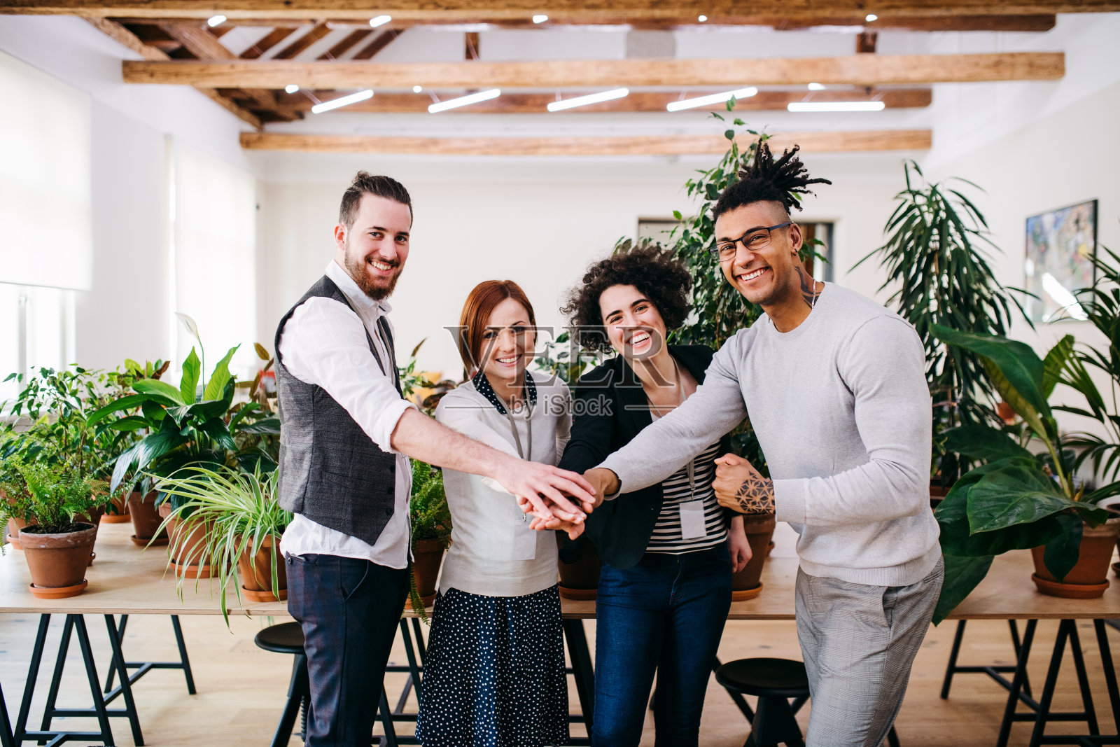 一群年轻的商人站在办公室里，双手合十。照片摄影图片