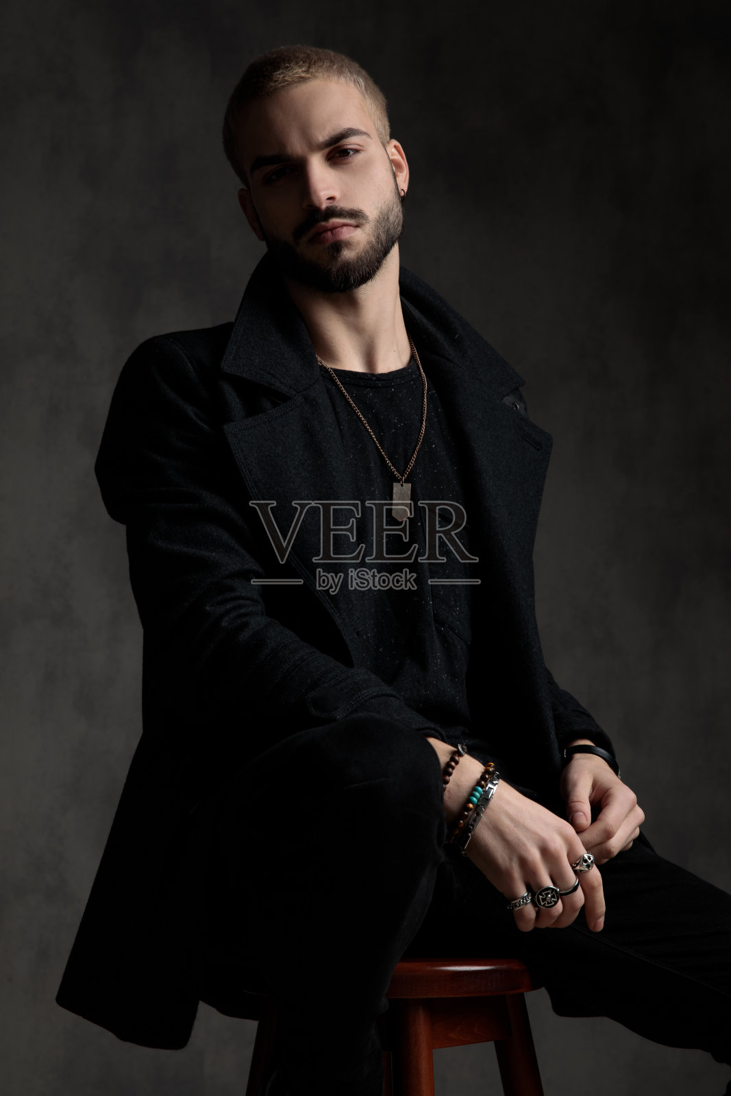 傲慢的时装模特坐在和穿着长大衣照片摄影图片