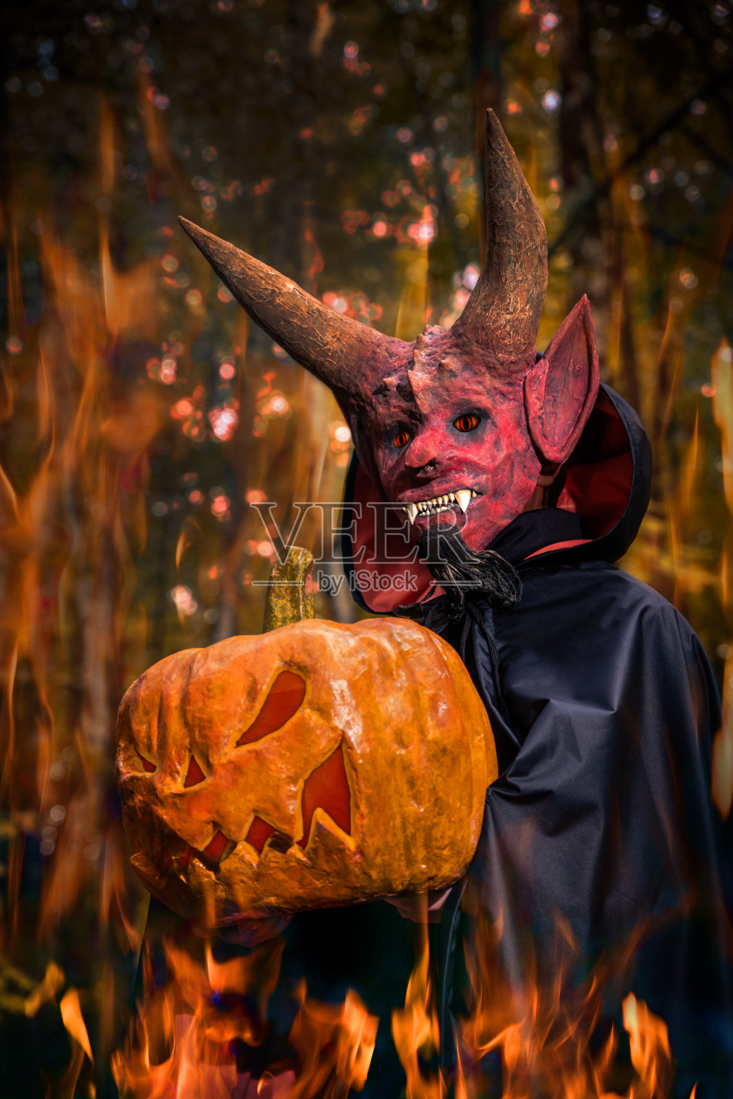 万圣节的时候，魔鬼手里拿着一个南瓜照片摄影图片