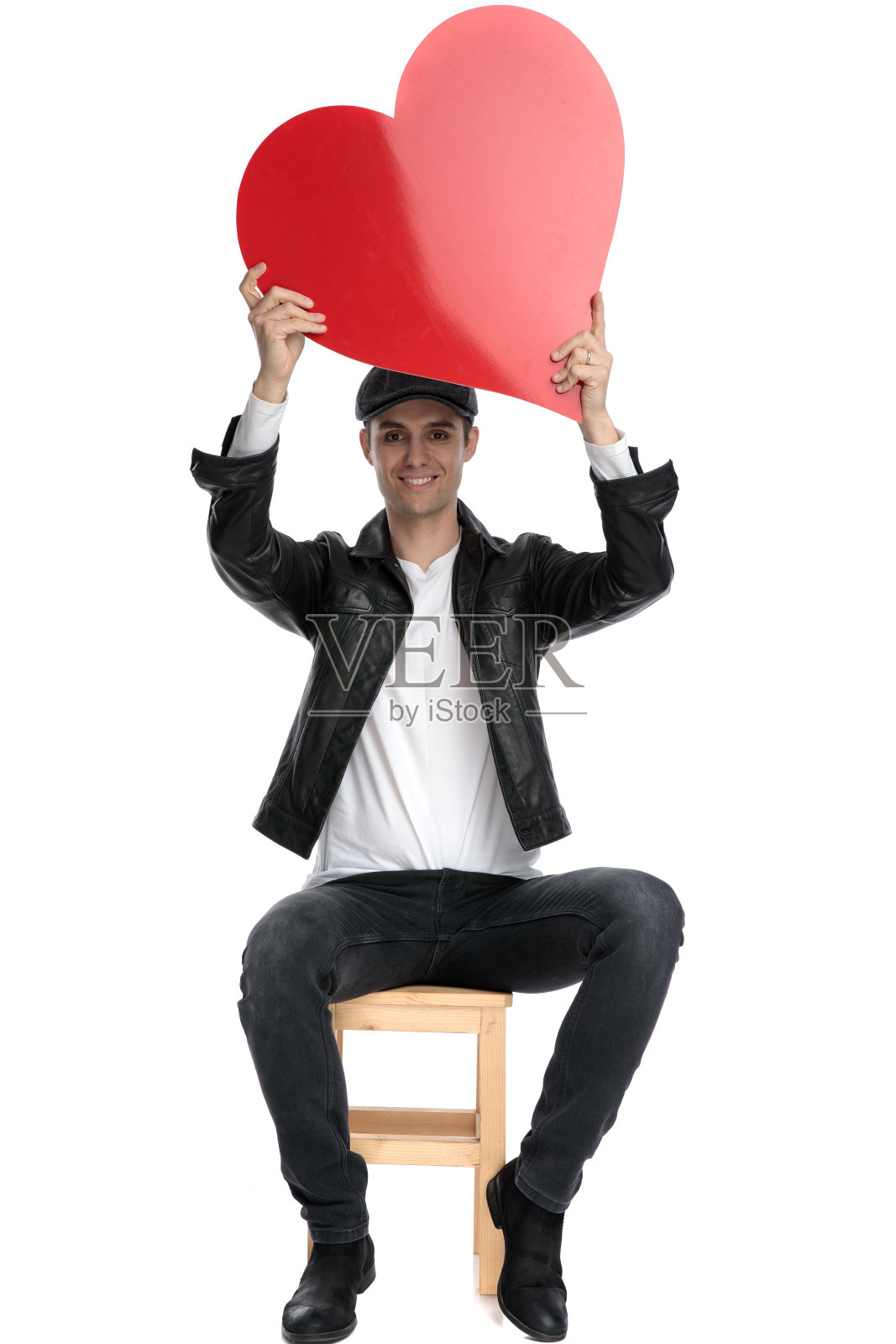 随意坐着的男人捧着一颗大大的红心在头顶快乐照片摄影图片