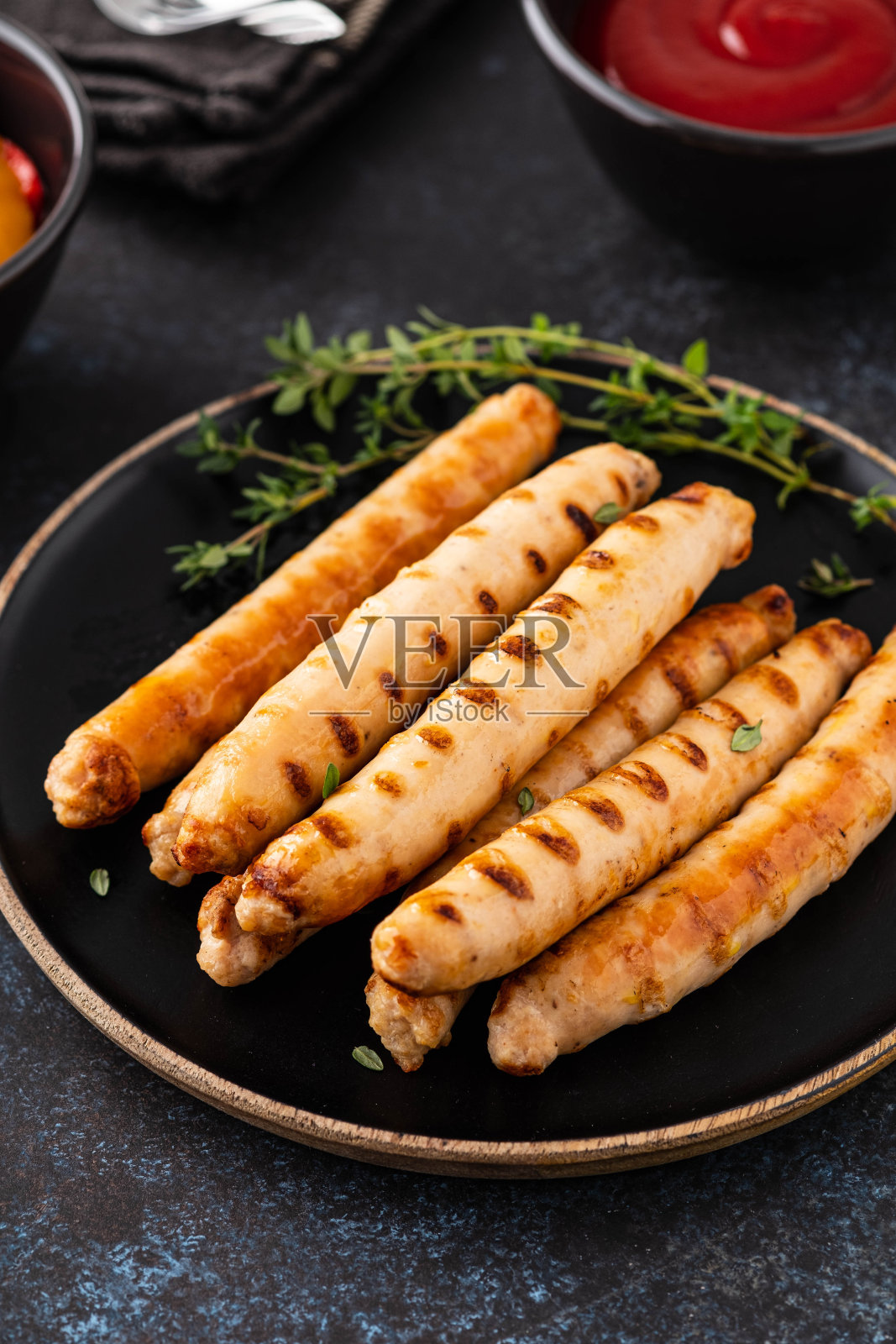 烤香肠放在黑盘子里，配上番茄酱和百里香。副本的空间。照片摄影图片