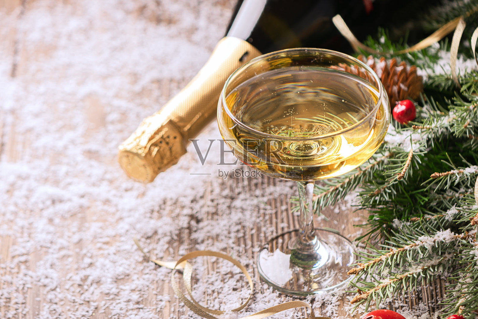 一杯香槟和一瓶香槟拉近了圣诞餐桌的距离。新年的概念。有选择性的重点。照片摄影图片