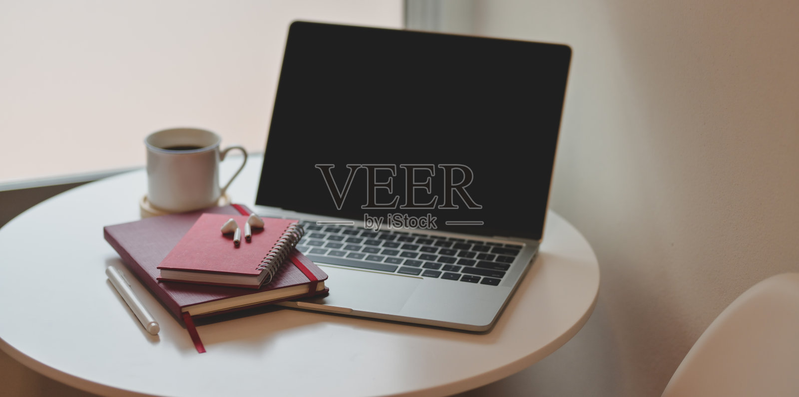 靠近窗户的白色木桌上放着笔记本和老式相机，工作场所极小照片摄影图片