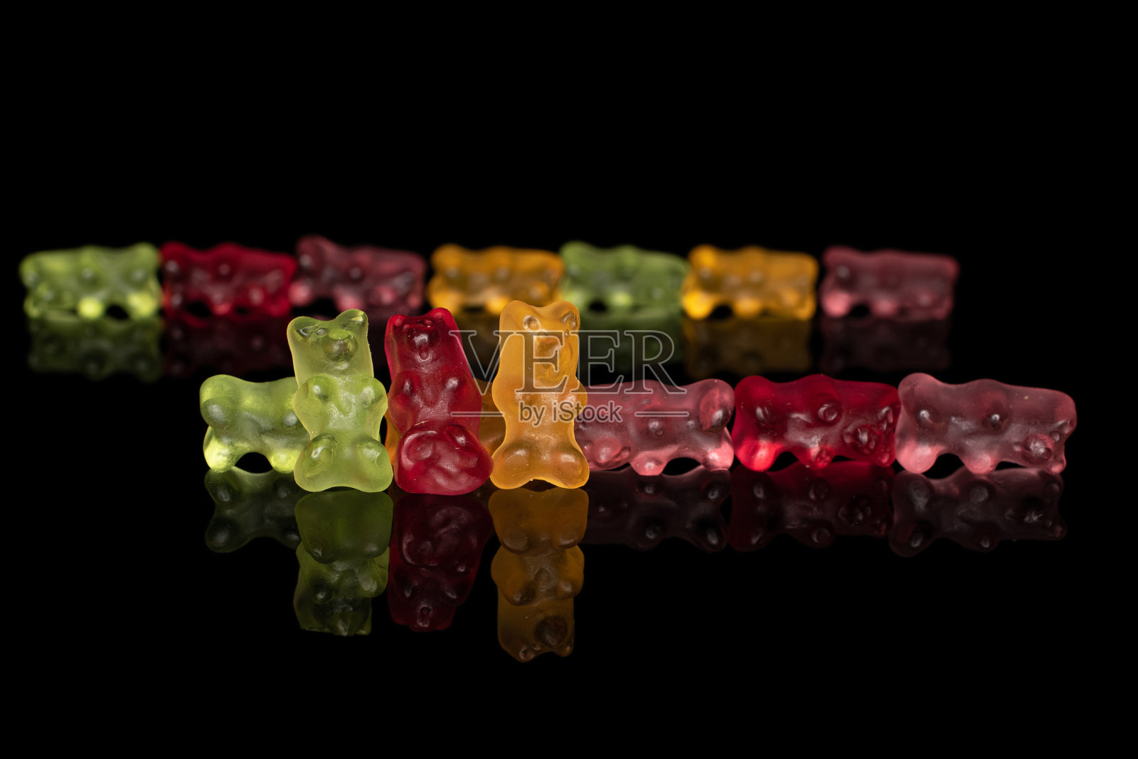 彩色小熊软糖孤立在黑色玻璃上照片摄影图片