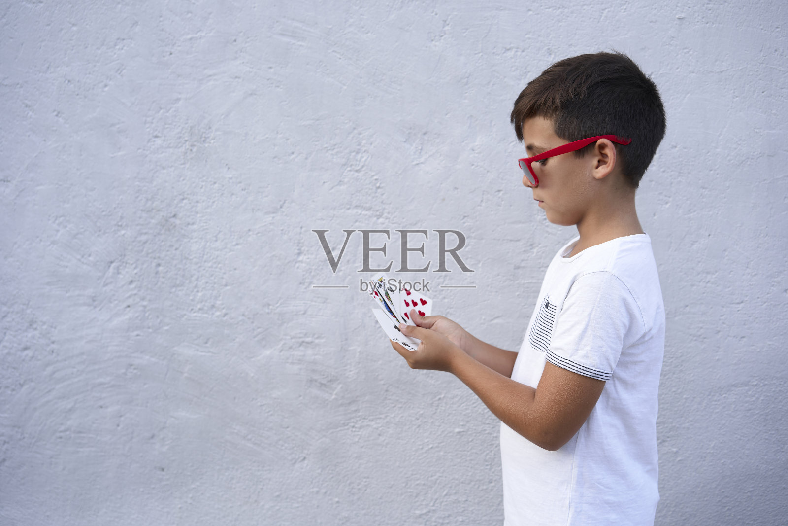 戴着红色太阳镜的男孩在打扑克照片摄影图片