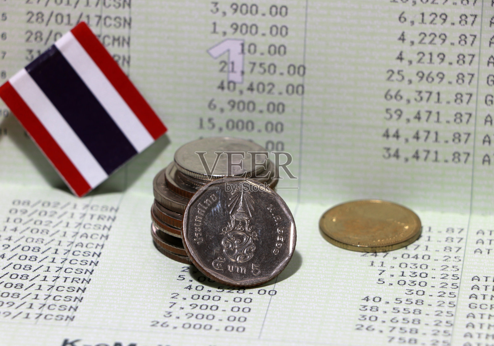 堆泰铢硬币钱和迷你泰国国旗上的书银行。照片摄影图片